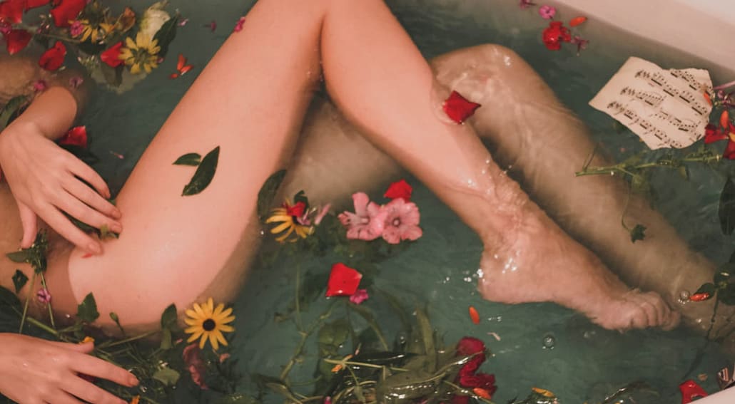 Woman's legs in bath tub with flowers - looks sexy, erotic