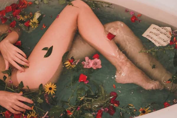 Woman's legs in bath tub with flowers - looks sexy, erotic